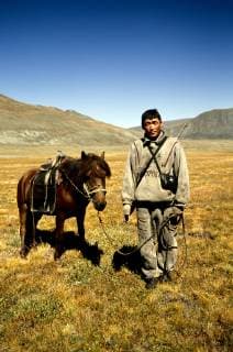 Portrait of a Kazakh Nomad proudly pausing with his horse for the photographer. Most of the nomads living in the Tavanbogd Atlai National Park are Kazakhs. Mongolian herders are also hunters, so they never leave their gers without old Russian binoculars and a rifle., Tavanbogd National Park Mongolia Copyright: OlivierxRenck 7282600040