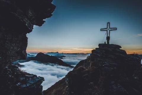 THEMENBILD - Wanderer mit dem Gipfelkreuz des Tristkogel waehrend des Sonnenaufgangs ueber den Wolken, aufgenommen am 16. September 2018 in Saalbach Hinterglemm, Oesterreich Hiker with the summit cross of the Tristkogel during the sunrise over the clouds, Saalbach Hinterglemm, Austria on 2018 09 16.