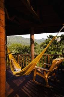 A person lays on a yellow hammok next to a chair at the deck of a cabin in Finca Argovia, Chiapas, Mexico., Chiapas Mexico model released Symbolfoto Copyright: MarcosxFerro 3329400030