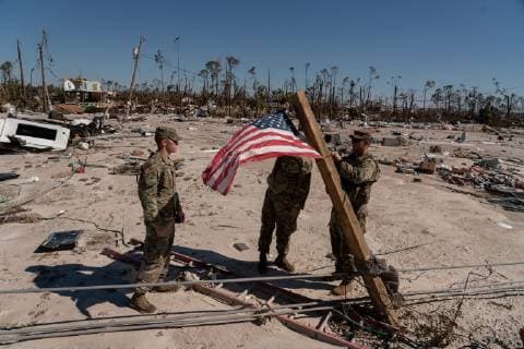 Spc. Sean Westmoreland, Spc. Herbert Joyner, and Pfc. Jeremy Grant, from the 153rd Charlie Troop in Tallahassee, hang the American flag on a 4x4 of debris after Hurricane Michael hit in Mexico Beach, Florida October 13, 2018.  WAP20181013549 KENxCEDENO