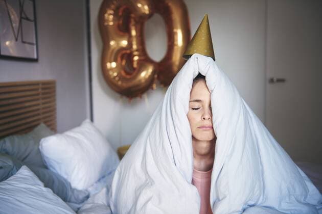 Sad woman celebrating her birthday, sitting on bed under blanket model released Symbolfoto property released  ABIF00982
