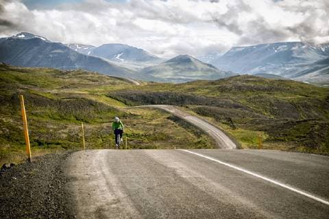 A Woman Cyclist Crests A Hill In The Mountains Of North Iceland, Siglufjordur North Iceland Iceland model released Symbolfoto Copyright: BrentxOlson OLBR000257