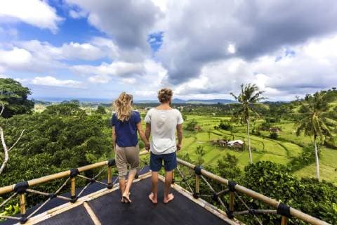 IMAGO Creative, Leben im Bamhaus Adult couple standing on tree house balcony and holding hands while admiring landscape, Bali, Indonesia, Candidasa Bali Indonesia model released Symbolfoto Copyright: KonstantinxTrubavin TRKO017692