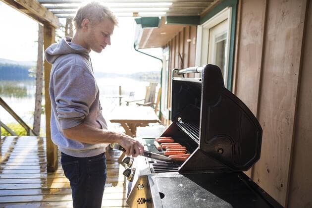 Side view of man cooking sausages on barbecue grill, Kamloops British Columbia Canada KICH016255 model released Symbolfoto property released Copyright: ChristopherxKimmel KICH016255
