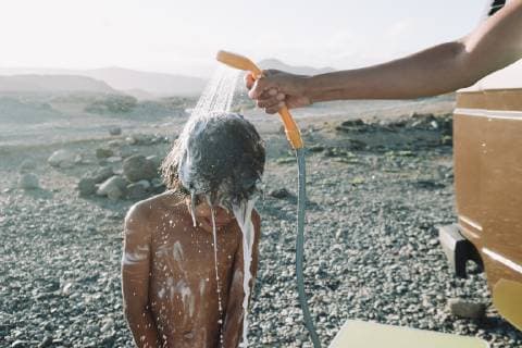 IMAGO Creative: Klimawandel - Nachhaltiges Reisen Boy takes shower outdoors on cobblestone beach, Tenerife, Canary Islands, Spain, Tenerife Canary Islands Spain VISE003988 model released Symbolfoto Copyright: SergioxVillalba VISE003988