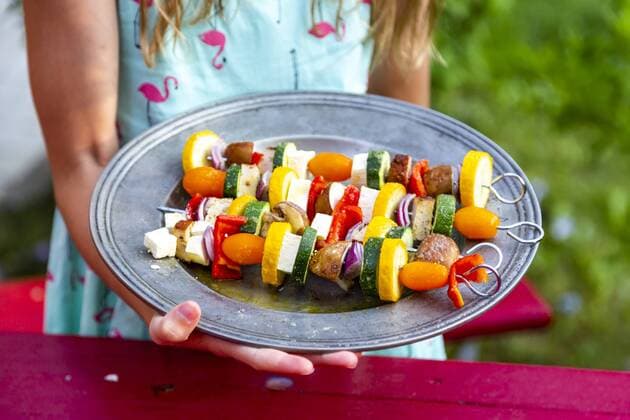 Girl holding plate with vegetarian grill skewers, tomato, yellow and green zucchini, tofu, feta, onion and champignon model released Symbolfoto  SARF03931