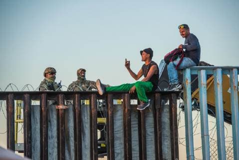 Nov 14, 2018 - Tijuana, Mexico - Asylum seekers from Central America, aka the Migrant Caravan , converse with US Border Patrol atop the border fence the US Mexico border in Tijuana. The forklifts were there to modify the border fence to add more concertina wire atop the fence. Tijuana Mexico - ZUMAs157 20181114_tim_s157_017 Copyright: xVitoxDixStefanox