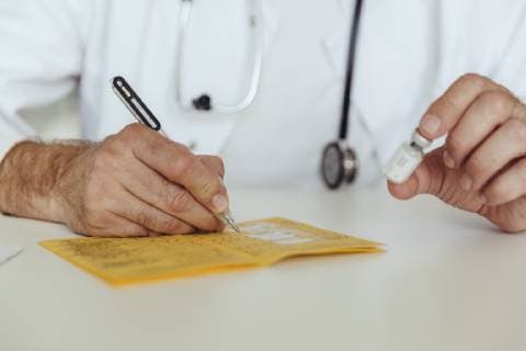 Doctor filling in immunization card model released Symbolfoto property released  MFF04478
