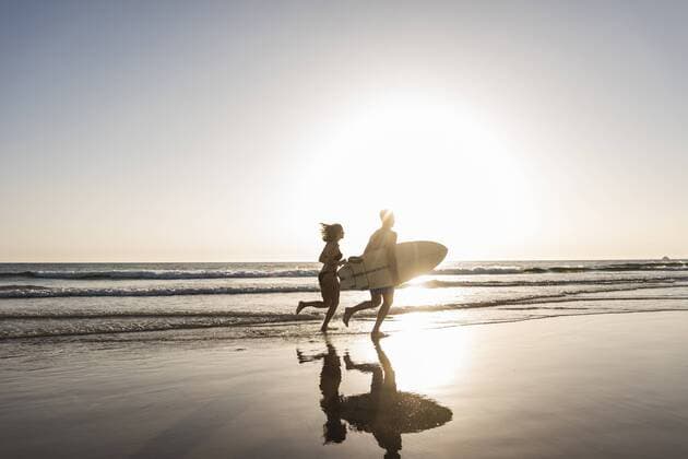 Young couple running on beach, carrying surfboard model released Symbolfoto  UUF15120