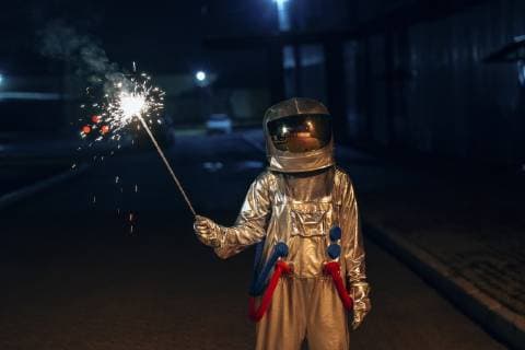 Spaceman standing outdoors at night holding sparkler model released Symbolfoto  VPIF00698