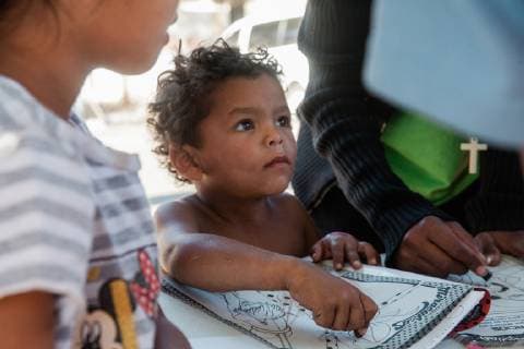 A group of volunteers from Groupo Unitad (United Group), a Christian group, work with childern at a table near the Benito Suarez shelter in Tijuana, Mexico on November 27, 2018. They brought coloring books to help lift the spirits and occupy their time.  TIJ2018112706 ARIANAxDREHSLER