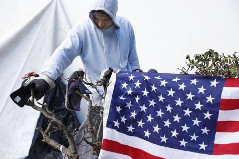Migrant caravan A migrant from Central America dries his shoes next to the American flag hung on a branch in Tijuana, Mexico, on Nov. 28, 2018. 