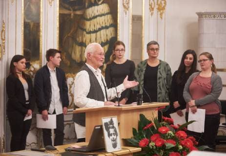 Preisträger Thilo Pohle (am Pult) und seine Filmgruppe Rothenburg im Hintergrund; vorne ein Porträt von Marion Samuel; Verleihung Marion-Samuel-Preis 2018 der Stiftung Erinnerung an die Dokumentarfilmgruppe Rothenburg ob der Tauber; Regierung von Schwaben, Rokoko-Saal, 29.11.2018, Verleihung Marion-Samuel-Preis 2018 der Stiftung Erinnerung an die Dokumentarfilmgruppe Rothenburg ob der Tauber