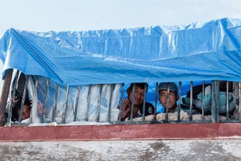 A group of friends from Honduras peer out from a shelter in Tijuana, Mexico on December 2, 2018. They traveled without their families, arrived 11 days ago and hope to go to college in the United States.  TJ2018120204 ARIANAxDREHSLER