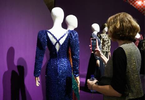 MOSCOW, RUSSIA - DECEMBER 4, 2018: A girl takes pictures of exhibits on display at an exhibition titled The Glamour of the 80s by Russian fashion historian Alexandre Vassiliev opened at the VDNKh exhibition centre. The exhibition shows a unique collection of the 1980s costumes by Chanel, Christian Dior, Yves Saint Laurent, Givenchy, Pierre Balmain, Claude Montana, and other fashion houses. Mikhail Tereshchenko TASS  TS099C8B