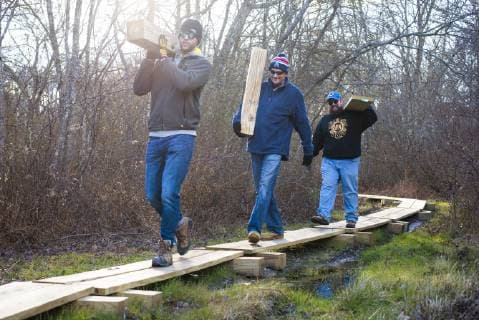IMAGO Creative: Zivildienst und ehrenamtliches Engagement Volunteers carrying planks while working together to build a boardwalk as part of a nature trail with The Nature Conservancy, Little Compton, Rhode Island, USA, Little Compton Rhode Island United States Copyright: CatexBrown BRCA003428