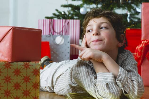 Boy lying on floor pointing at Christmas presents  Copyright: FrédéricxCirou B10926927