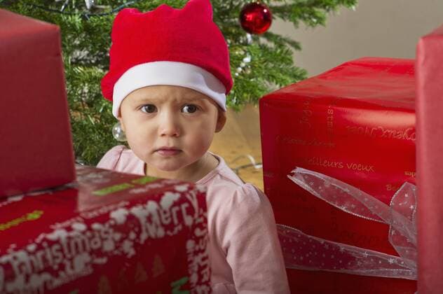 Baby girl sitting by Christmas presents with sulky expression on face  Copyright: FrédéricxCirou B11626827