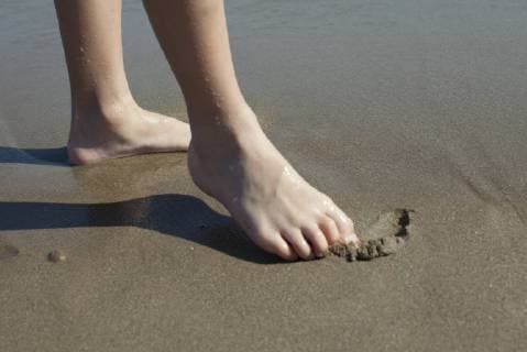 Child drawing in wet sand with foot, cropped  Copyright: AntoinexArraou B58940216