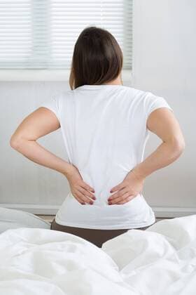  Woman With Back Pain Sitting On Bed model released Symbolfoto  Copyright: xAndreyPopovx Panthermedia15975615