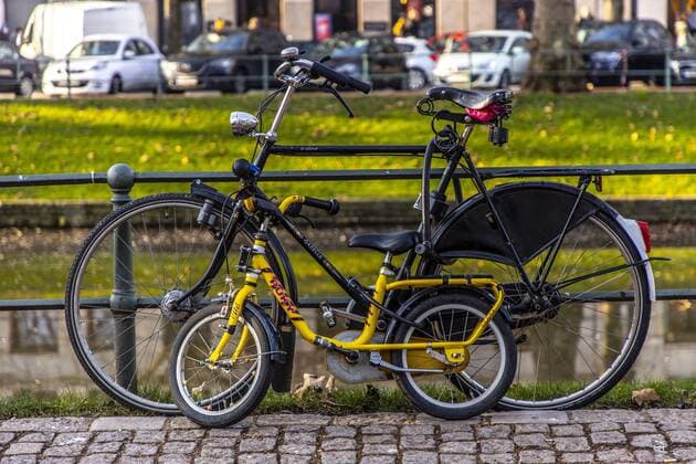 Fahrrad eines Erwachsenen und Kinderfahrrad, stehen abgeschlossen an einem Zaun,