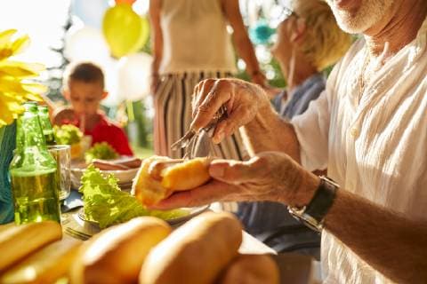 Senior man preparing a hot dog on a garden party model released Symbolfoto property released  ZEDF01618
