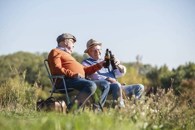 Two old friends sitting in the fields, drinking beer, talking about old times model released Symbolfoto  UUF15478