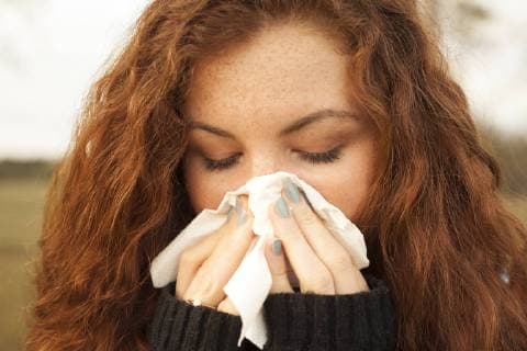 Redheaded young woman blowing nose in nature model released Symbolfoto  FCF01297