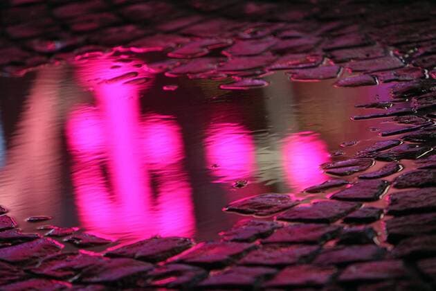 Telekom Filiale spiegelt sich in einer Regenpfütze in der Innenstadt von Bonn am Abend, Nordrhein Westfalen, Deutschland