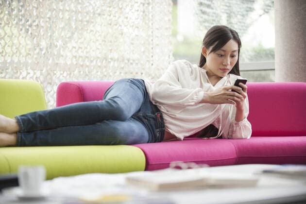 Woman relaxing at home with smartphone  Copyright: OdilonxDimier B06980621