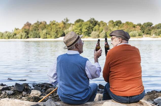 Old friends sitting by the riverside, drinking beer model released Symbolfoto  UUF15518