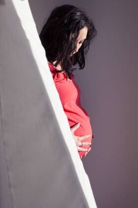 Pregnant woman holding stomach, looking down  Copyright: Anne-SophiexBost B45700639
