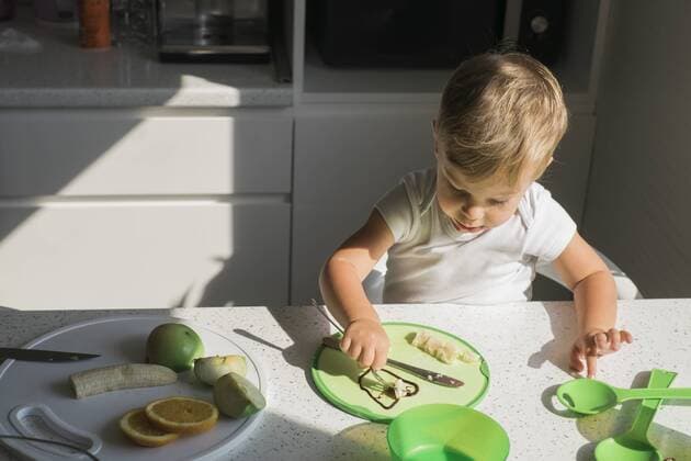 Little boy sitting at table in the kitchen eating fruits model released Symbolfoto property released  MOMF00533