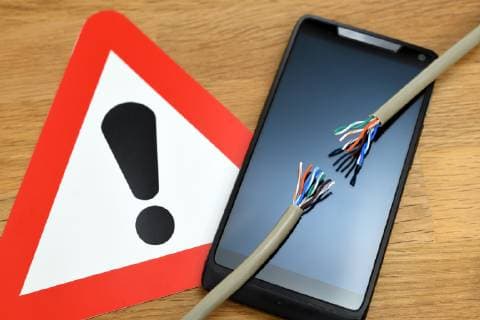 Smartphone mit zerrissenem Kabel und Warnschild, Symbolfoto Funkloch *** Smartphone with torn cable and warning sign Symbolfoto Funkloch ** NUR FUER REDAKTIONELLE ZWECKE ** EDITORIAL USE ONLY **