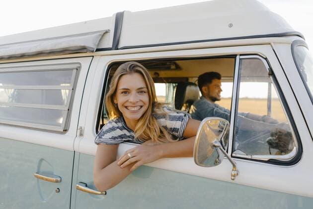 Portrait of happy woman leaning out of window of a camper van with man driving model released Symbolfoto  GUSF01412