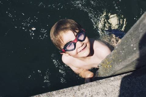 Boy with goggles swimming in water  Copyright: Anne-SophiexBost B53815531