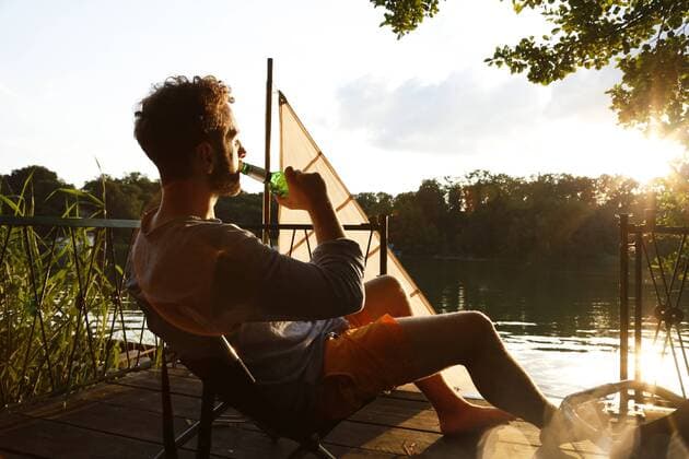 Young man with drinking a beer on a jetty next to sailing boat model released Symbolfoto  FKF02847