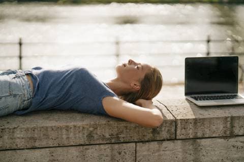 Young woman lying on a wall next to laptop model released Symbolfoto  GUSF01624