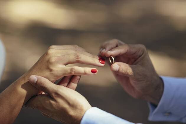 Groom putting wedding ring on finger of bride, close up model released Symbolfoto  JSMF00594