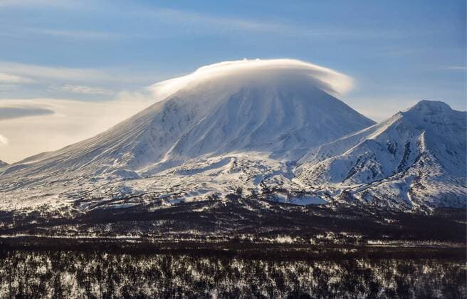 KAMCHATKA TERRITORY, RUSSIA - FEBRUARY 22, 2019: An aerial view of volcanoes Mount Khodutka (L) and Mount Priyomysh in South Kamchatka Nature Park on the Kamchatka Peninsula in Russia s Far East; South Kamchatka Nature Park was created in 1995 and included in the UNESCO World Cultural and Natural Heritage List under the name of Volcanoes of Kamchatka, in 1996; the landscape of South Kamchatka Nature Park features active volcanoes (stratovolcanoes) and glaciers. Yuri Smityuk TASS  TS0A1EF0