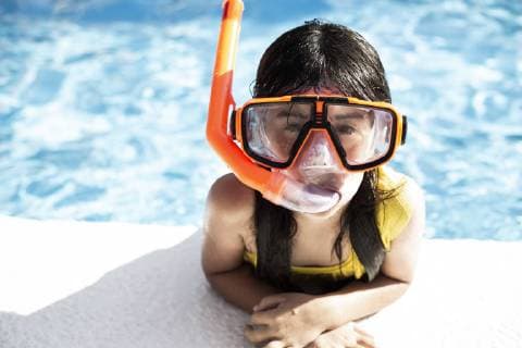 Portrait of little girl wearing snorkel and oversized diving goggles leaning on poolside model released Symbolfoto  ERRF00162