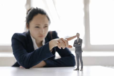 Businesswoman watching businessman figurine, standing on her desk model released Symbolfoto property released  FLAF00078