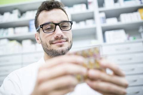 Smiling pharmacist holding tablet package in pharmacy model released Symbolfoto property released  WESTF23930