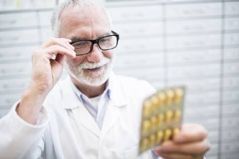 Smiling pharmacist holding tablet package in pharmacy model released Symbolfoto property released  WESTF23961
