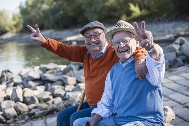 Two old friends sitting by the riverside, having fun model released Symbolfoto  UUF15505