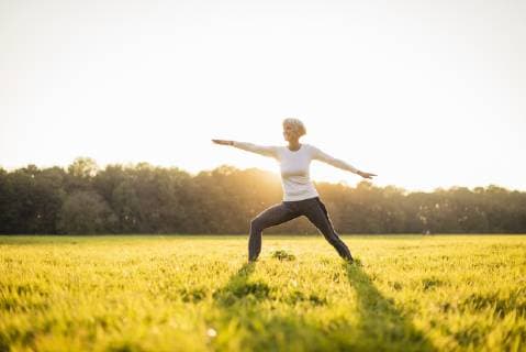 Senior woman doing yoga on rural meadow at sunset model released Symbolfoto  DIGF05474