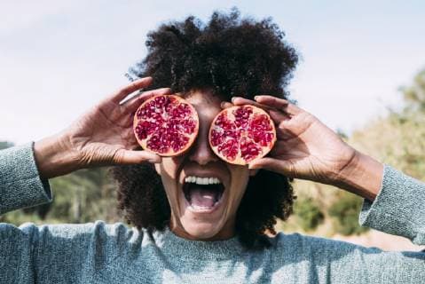IMAGO Creative: Landleben - Alfresco, Draußen Woman standing in the countryside, covering eyes with halved pomegranates model released Symbolfoto property released  GEMF02825