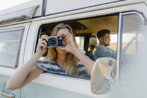 Woman taking picture out of window of a camper van with man driving model released Symbolfoto  GUSF01422