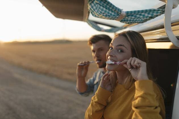 Couple brushing teeth at camper van in rural landscape at sunset model released Symbolfoto  GUSF01542