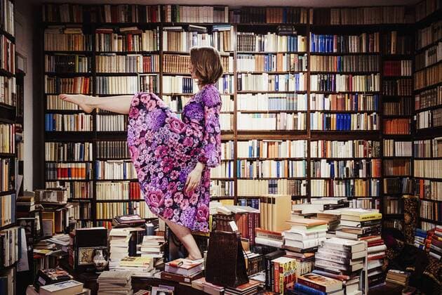 Exuberant woman dancing on book stacks in library  Copyright: SvenxHagolani fStopImages1808032
